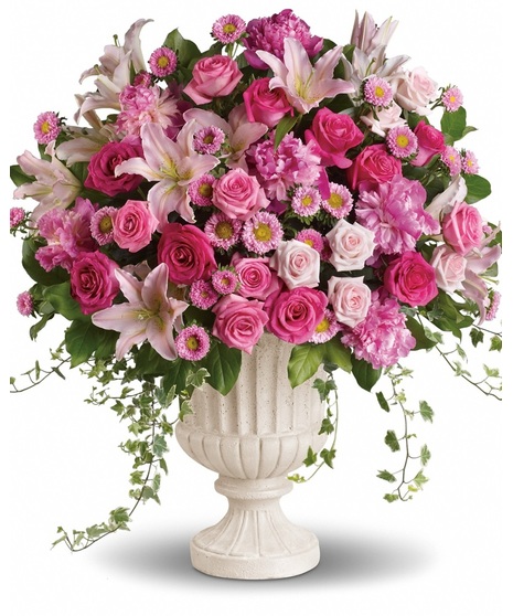 A pink arrangement in a classical urn with pink peonies, roses, lilies and asters