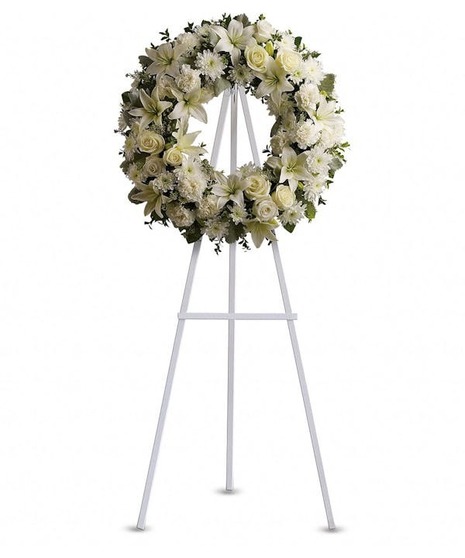 A round wreath with white flowers on an easel.