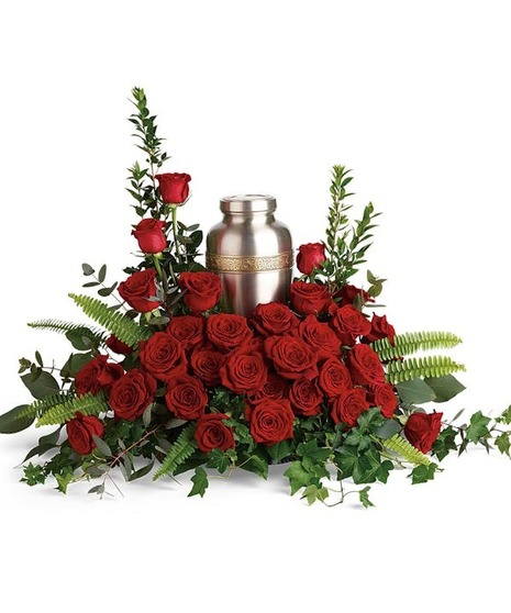 Red roses and delicate greenery around an urn.