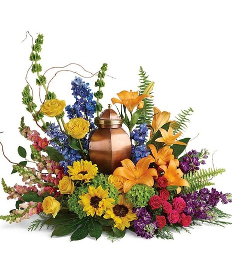 Hydrangea, roses, and sunflowers arranged around a cremation urn