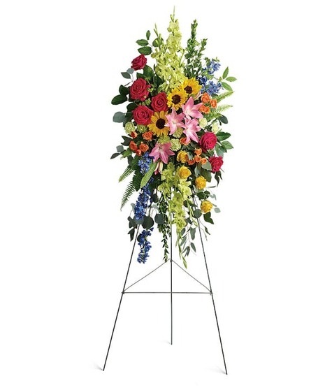 A rainbow of colorful flowers arranged in a spray to honor one who has passed